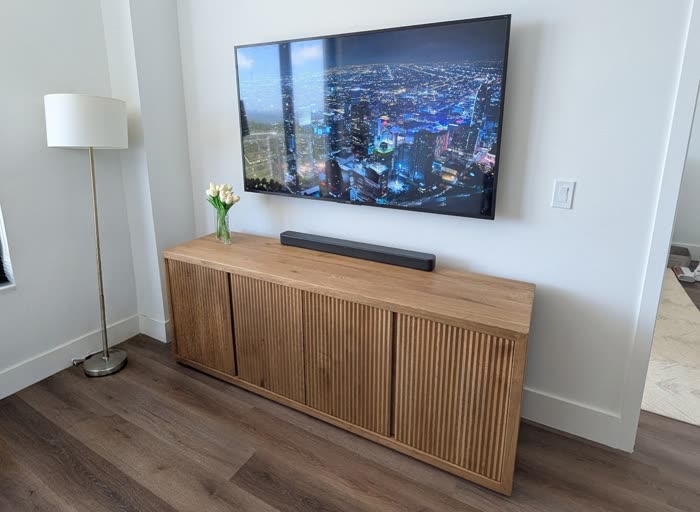 Finished install, TV above fluted-wood media cabinet