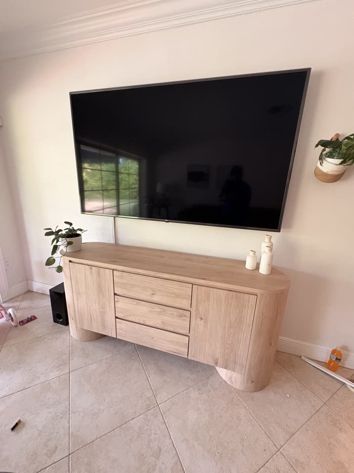 Finished install, large TV above light-wood media console